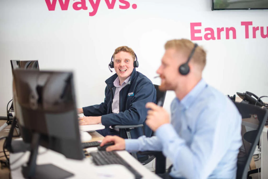 Male Wayv Talk Employees wearing telecommunication headset smiling at each other