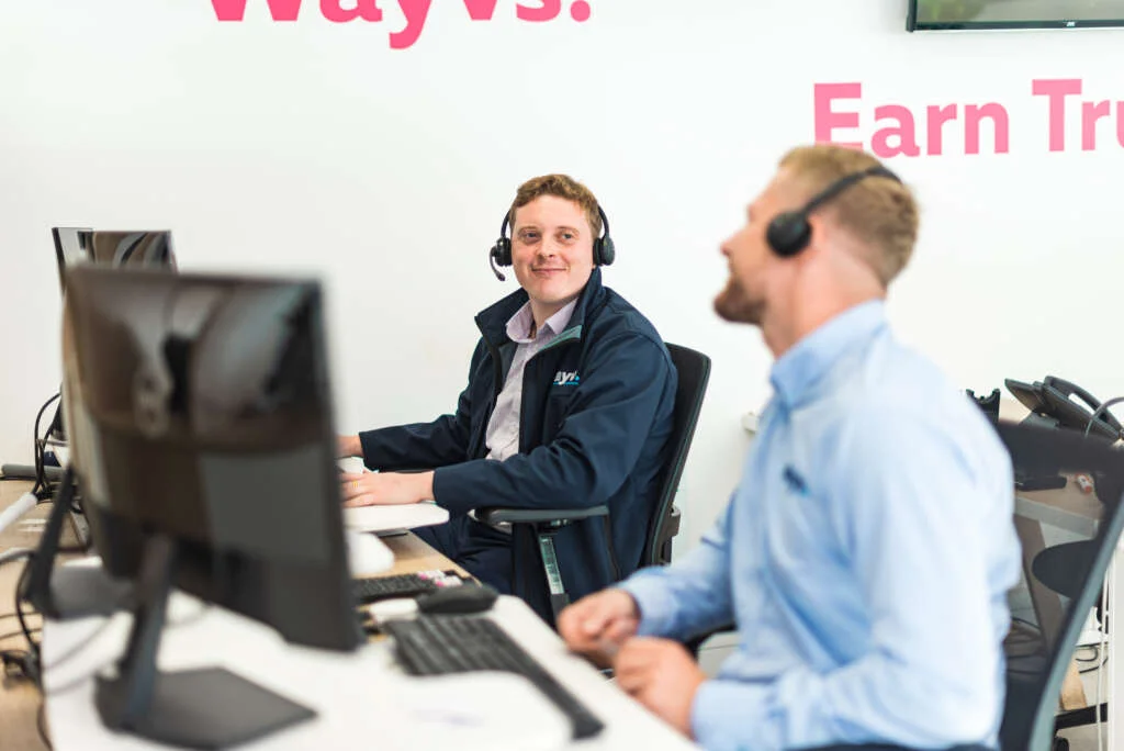 Male Wayv Talk Employees wearing telecommunication headset smiling at each other