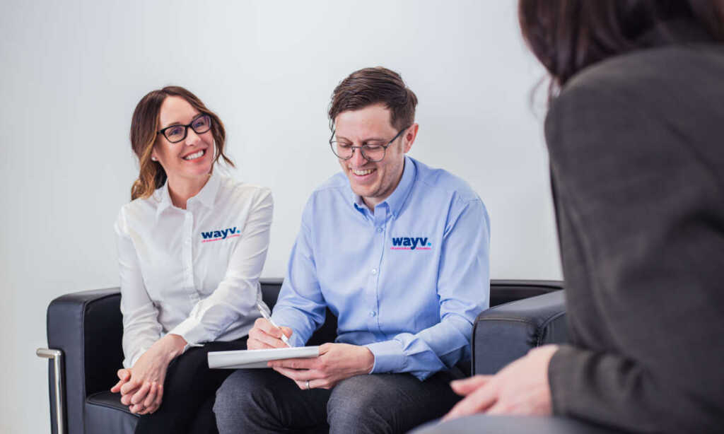 Male and female wayv talk employees laughing with a customer while making notes