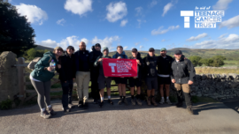 Team Wayv holding up a sign for Teenage Cancer Trust after completing a hike and over £10,000