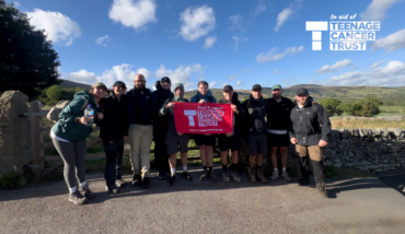 Team Wayv holding up a sign for Teenage Cancer Trust after completing a hike and over £10,000