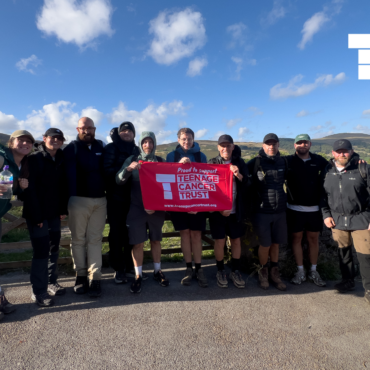Team Wayv holding up a sign for Teenage Cancer Trust after completing a hike and over £10,000